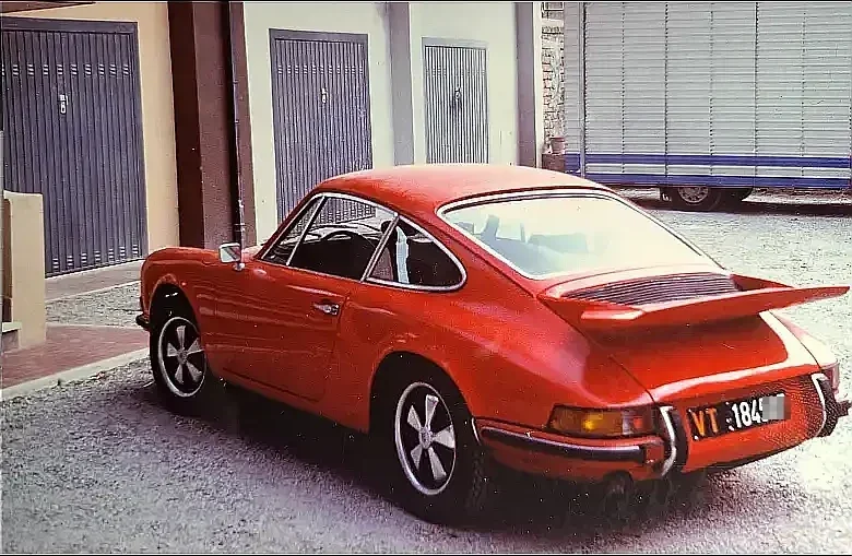 a Porsche 911 1969 red, in good condition, parked in the garden, rear three-quarter shot in daylight.
