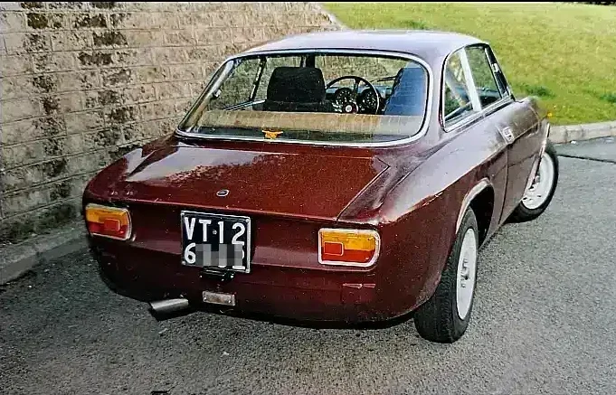 Alfa Romeo GT Junior 1300 cc, dark red colour, in good condition, without bumpers, rear three-quarter shot.