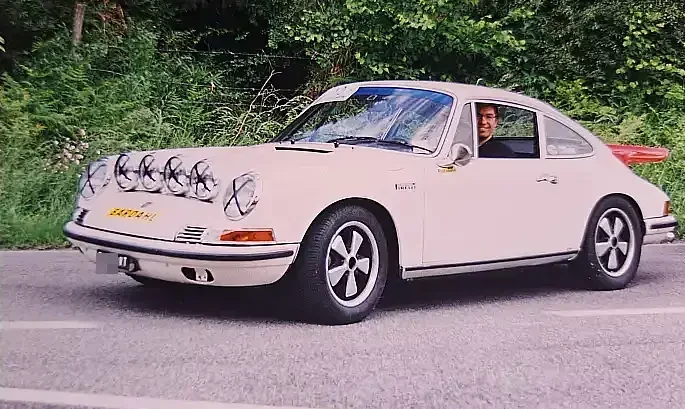 Porsche 911 s white, 1969, with extra headlights on the bonnet and extra tail wing at the back. Front three-quarter shot.