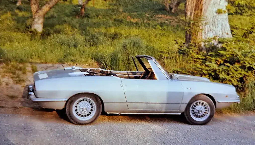 A Fiat 850 coupe silver colour, convertible car, photo taken from the right side and spoked wheels.
