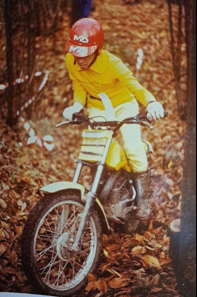 A SWM TL 320 MW motorcycle, yellow colour, climbing a hill in the forest in a trial club race section.