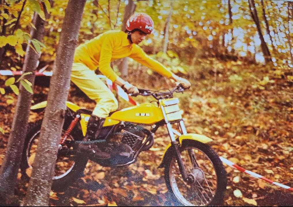 The rider is on his SWM 320 bike in a trial race section in the forest.